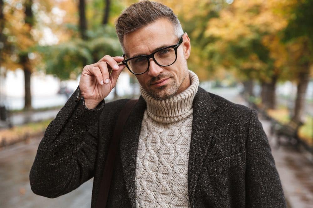 A man in mid 30s wearing high end eyewear brand designer frame glasses at a park