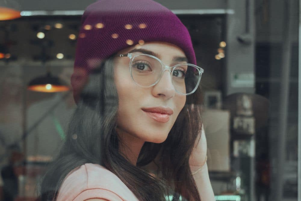 A young woman with beanie wearing unique designer frame glasses