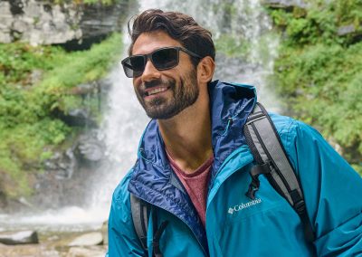 A man hiking in the rainforest wearing columbia sunglasses in black frame