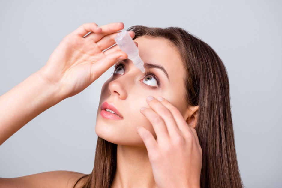 a woman putting eye drop in her eye