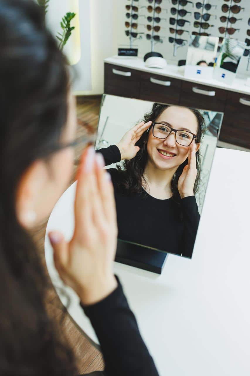 Young-woman-glasses-styling-fitting-consultation Young woman trying on glasses during eyewear styling consultation