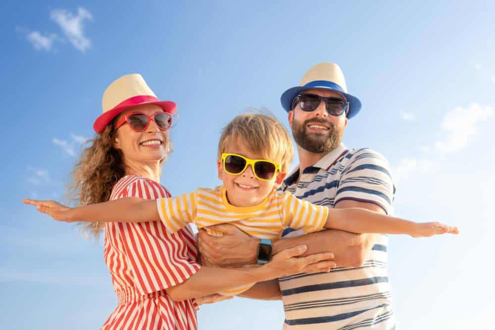 Mother and Father holding son posing all wearing sunglasses