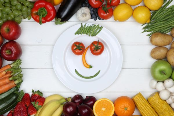 Healthy eating with smiling face of vegetables and fruit on a plate.