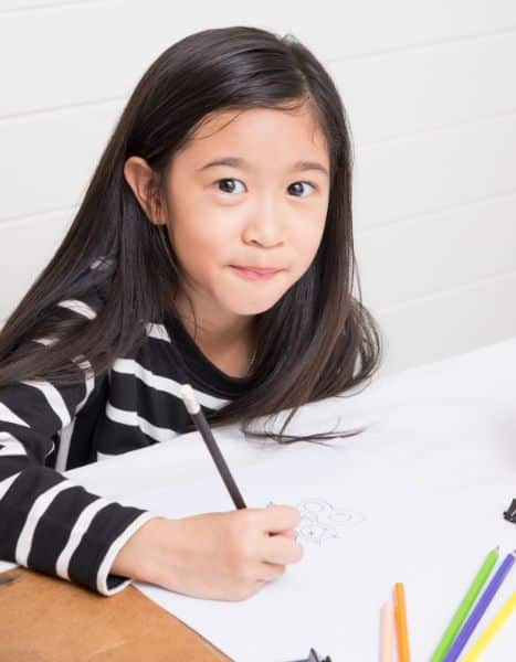 little asian girl drawing in class