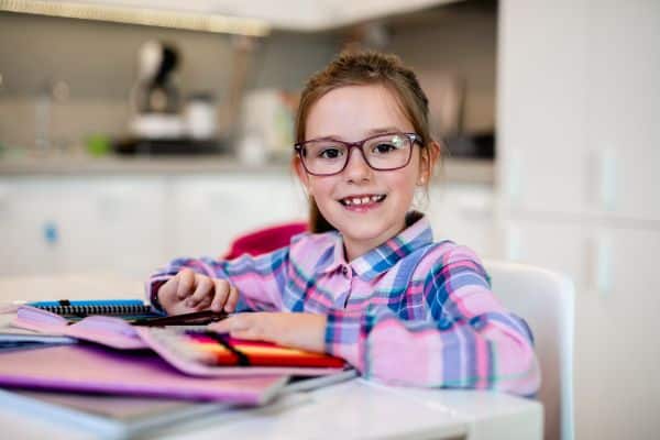 a little girl wearing myopia glasses doing her homework