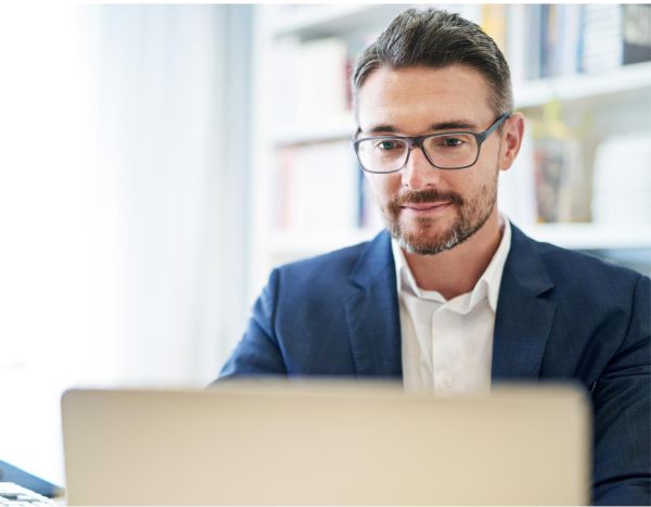 an mature businessman wearing glasses working on laptop in the office