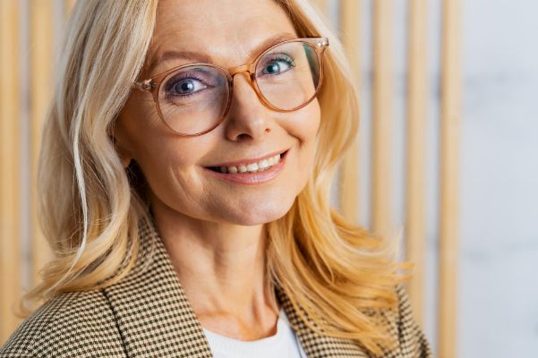 Middle aged woman wearing glasses sitting at computer desk in the office