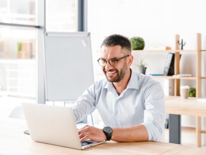 an office man wearing glasses working on laptop in the office