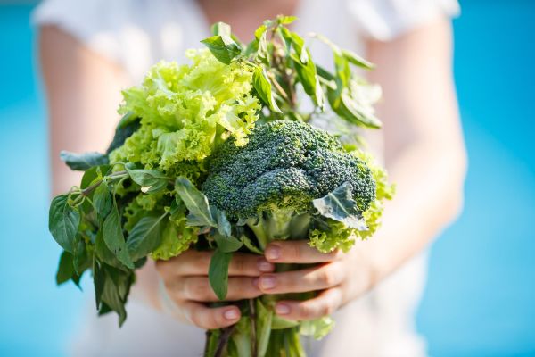 woman holding a bunch of vegetables to maintain good eye health.