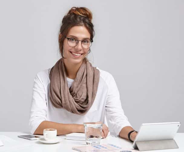 a smiling woman wearing glasses working at the desk
