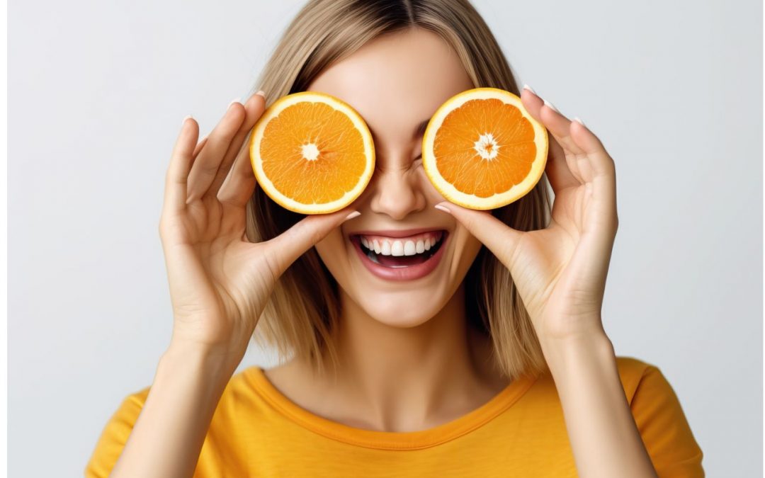 Young woman placing orange on her eyes. Healthy diet for healthy eyes