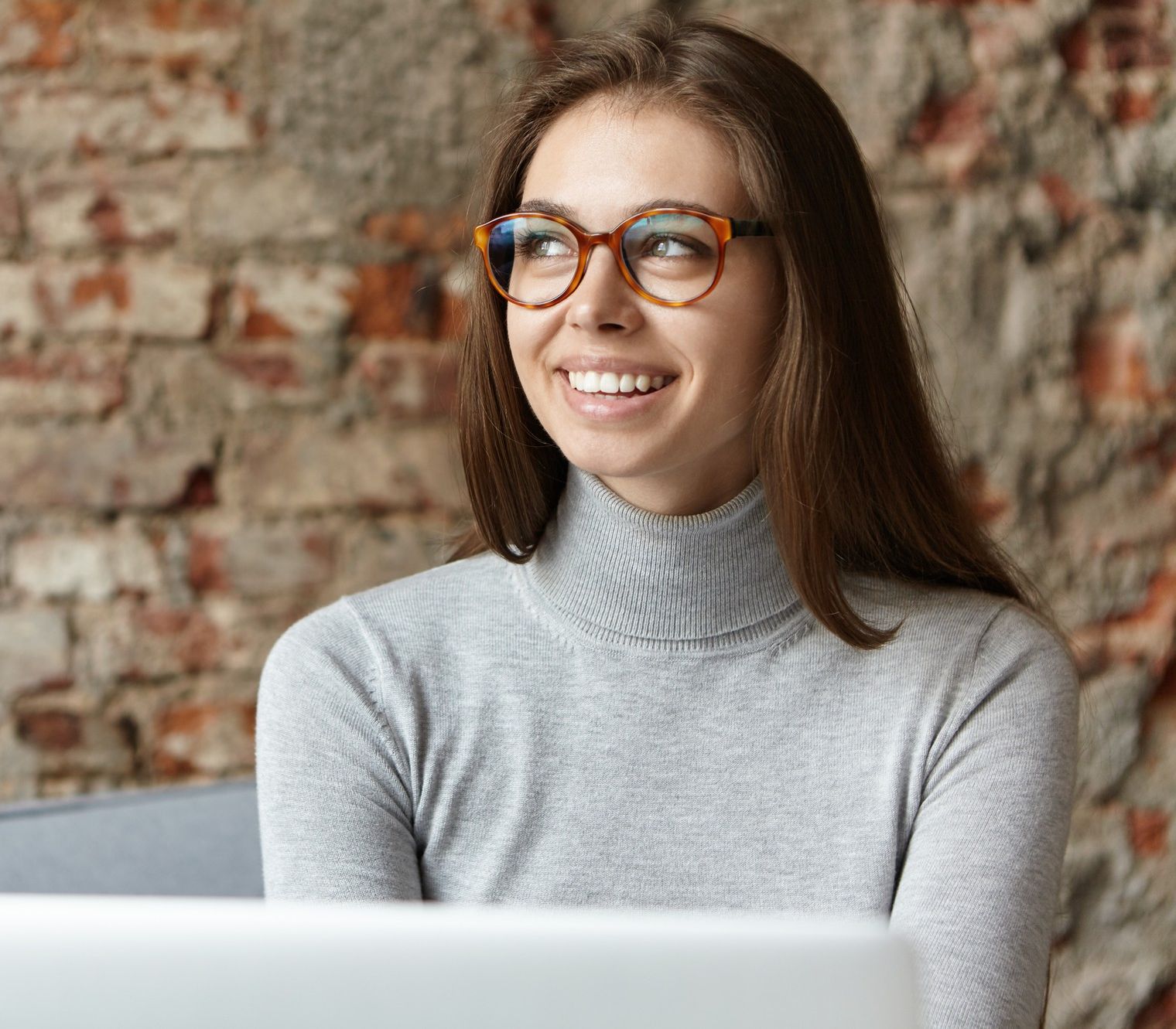 young woman wearing grey turtleneck and eyeglasses working in the office