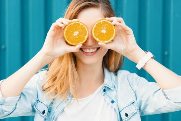 A young woman holding two halves oranges promote healthy diet for healthy eyes